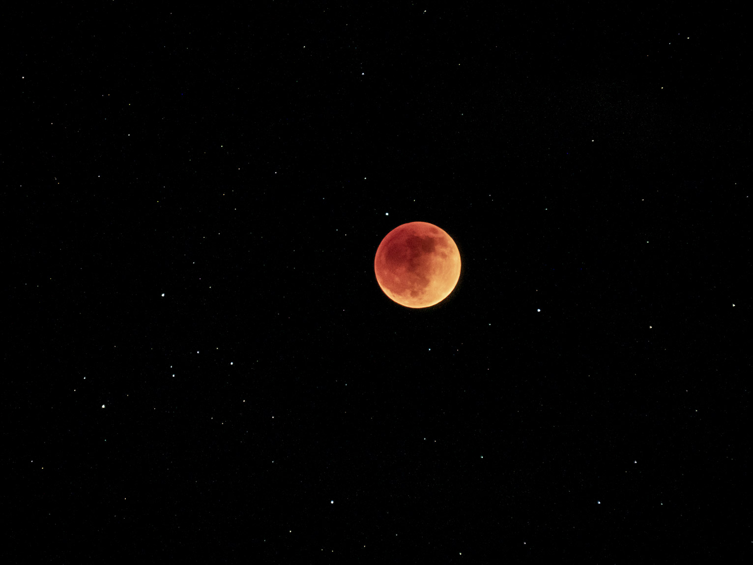 The blood moon hanging in the sky with stars